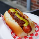 Frisch selbstgemachte original amerikanische Coney Island Hot Dogs aus Detroit-Style: saftiges Rindswürstchen im weichen Bun, überladen mit würziger Chili-Sauce ohne Bohnen, gelbem Senf und feinen Zwiebelwürfeln.